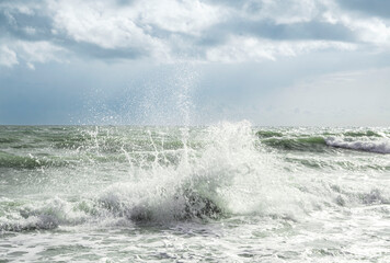 Fototapeta premium A massive wave erupts into a spectacular high spray against a dramatic cloudy sky on the Vietnamese coast. Raw power of the South China Sea captured in motion.