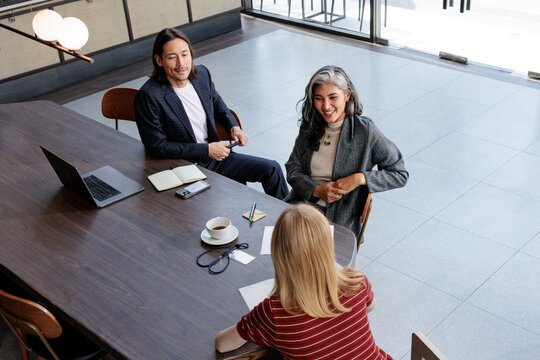 Business meeting with laptop, coffee, and smiling participants.