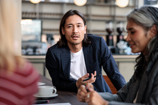 Business meeting in progress, man explaining with pen.