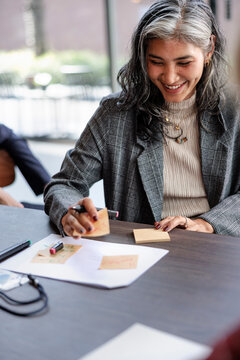 Smiling woman brainstorming with sticky notes at a table.