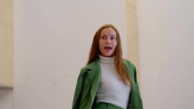 Teenage girl in green suit singing and dancing with a smile, taking part in school theatre casting and showing her vocal and acting talent.