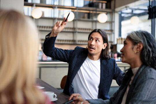 Business meeting, man explains with pen in hand.