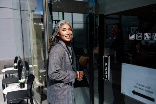 Woman exits hotel entrance with confidence and a smile.