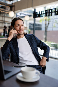 Man in blazer talks on mobile phone at cafe.