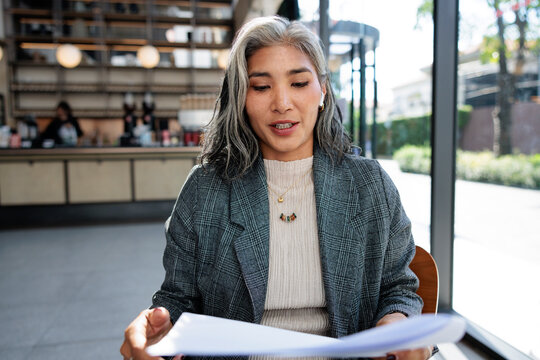 Woman reviews documents in a bright cafe setting