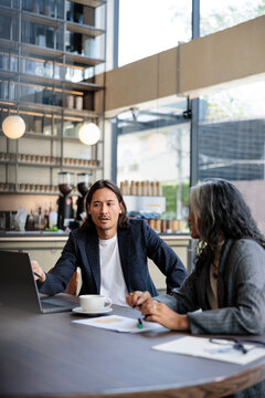 Business meeting at a cafe with laptop and coffee.