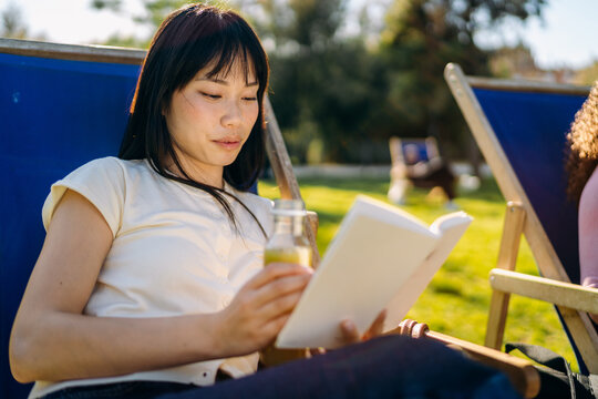 A woman reads a book sitting outdoors