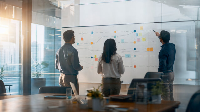 Business team mapping abstract strategy roadmap on large office whiteboard