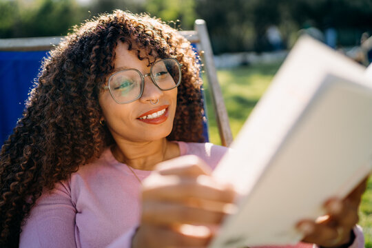A woman reads a book sitting outdoors