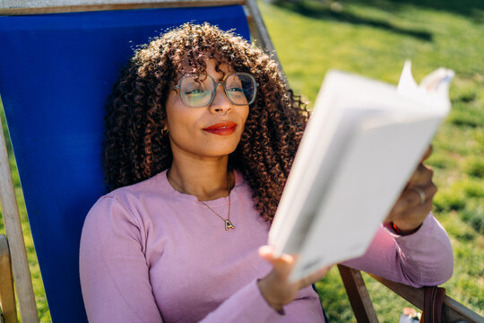 A woman reads a book sitting outdoors