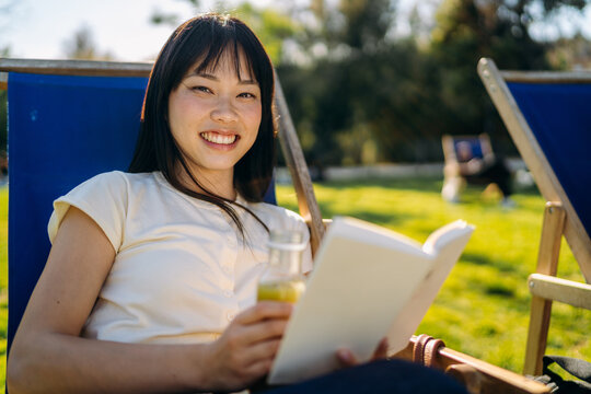 A woman reads a book sitting outdoors