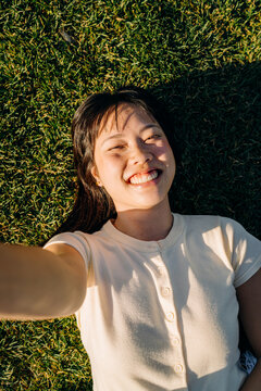 A woman takes a selfie lying on the grass