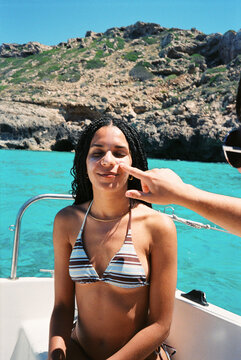 Funny analog portrait of woman with sunscreen on a boat