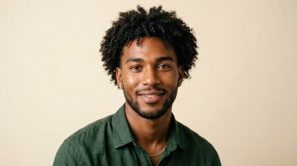 Obraz premium A man with curly hair wearing a green shirt, standing against a beige background.