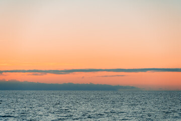 Fototapeta premium Panoramic ocean sunset with orange dusk sky gradient and calm water surface