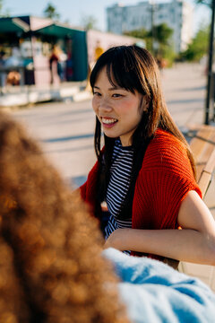 Two women are talking sitting on a bench