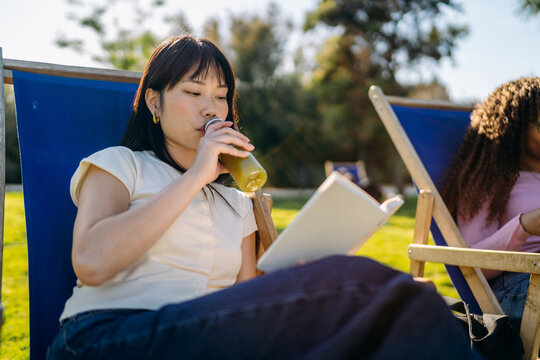 A woman reads a book sitting outdoors