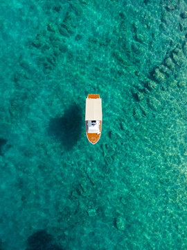 Boat sails on Clear Water in a Tropical Location, aerial top view