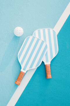 Two Pickleball Paddles and Ball on Court
