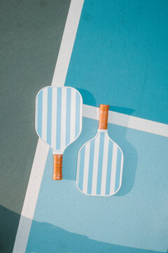Two Pickleball Paddles on Blue Court