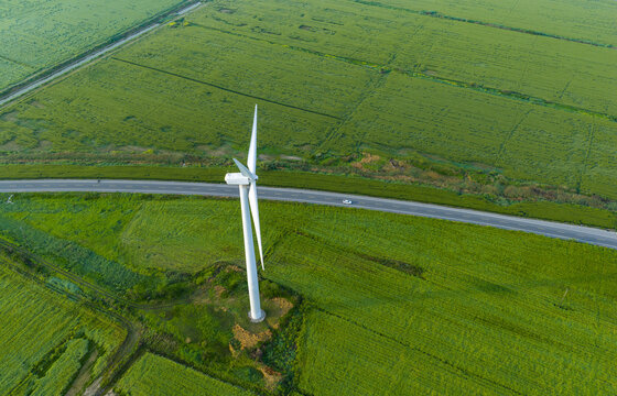  single wind turbine over green farmland beside rural road
