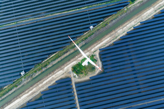 wind turbine surrounded by vast solar panel arrays