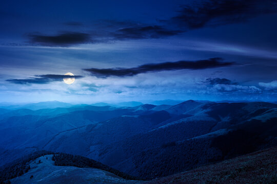 mysterious mountain landscape in summer at night. travel ukraine background. full moon over rolling hill in dappled light. scenic view of borzhava ridge. carpathian mountain scenery