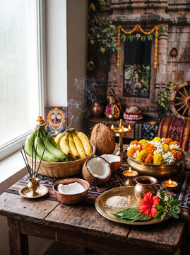 A traditional Hindu puja altar is beautifully arranged with sacred offerings, oil lamps, incense, flowers, bananas, and coconuts in preparation for a devotional worship ceremony.