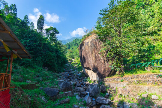 Apple shaped huge rock called "Apple Stone", with river flowing by side and blue sky in background , at Jhalong, Dooars, West Bengal - India