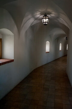 Historic corridor with arches. Medieval lantern casts shadows