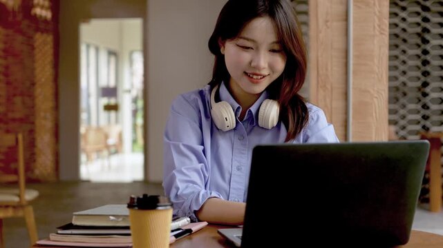 Young Asian Businesswoman Working Remotely with Laptop and Smartphone in Traditional Wooden Cafe, Digital Nomad Lifestyle