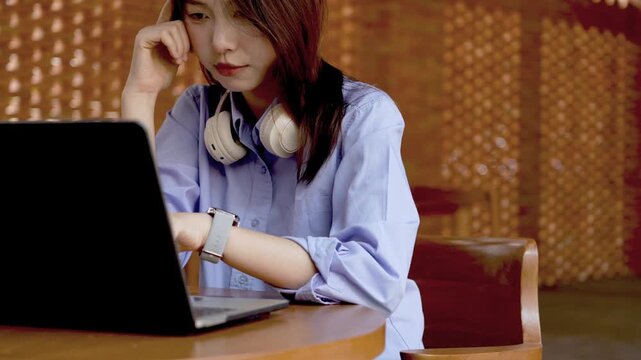 Young Asian Businesswoman Working Remotely with Laptop and Smartphone in Traditional Wooden Cafe, Digital Nomad Lifestyle