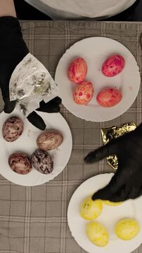 Woman's hands decorating easter eggs with gold leaf