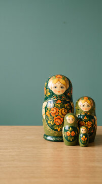 Traditional Russian Matryoshka Dolls Set Displayed On Wooden Surface Against Green Wall