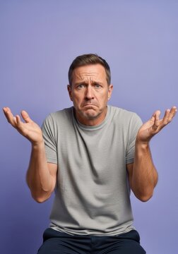 Confused Middle-Aged Man Shrugging Shoulders with Uncertain Expression on Purple Background
