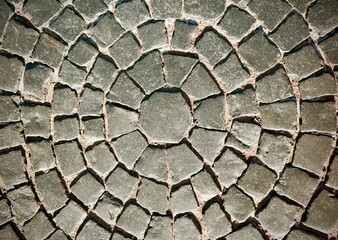 textured grey cobblestone pavement arranged in concentric circular pattern. Weathered stone walkway background for landscape architecture, hardscaping, and vintage design. Top down close up view © Kisandaya