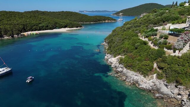 4K drone flythrough shot along narrow turquoise sea channel between green coastlines in Sivota
