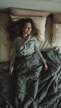 top view tired woman falls lies onto a pillow bed to rest, joy smiling face concept relax, soft mattress cozy home room. happy carefree girl is getting ready for bed have good sleep. vertical video.