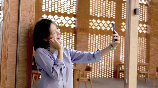 Young Asian Businesswoman Working Remotely with Laptop and Smartphone in Traditional Wooden Cafe, Digital Nomad Lifestyle