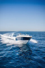 Fototapeta premium Front view of a motorboat cruising over the calm ocean with speed