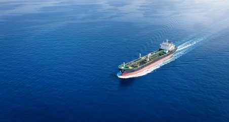 Aerial view of a crude oil or chemical goods tanker sailing with speed over calm ocean with copy space as a banner © moofushi