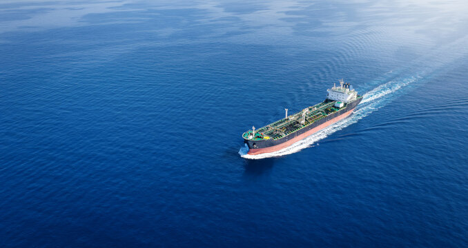 Aerial view of a crude oil or chemical goods tanker sailing with speed over calm ocean with copy space as a banner
