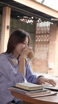 Young Asian Businesswoman Working Remotely with Laptop and Smartphone in Traditional Wooden Cafe, Digital Nomad Lifestyle