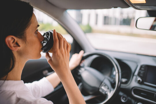 Woman drinking takeaway coffee while driving a car on her daily commute