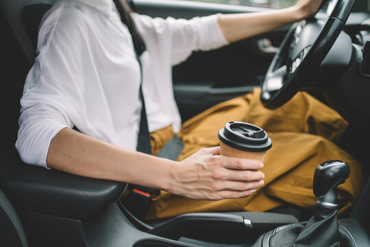 Close up of woman holding takeaway coffee while driving a car