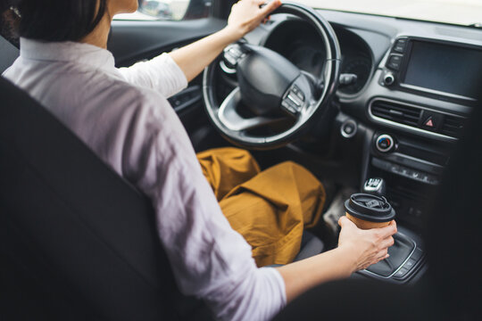Cropped shot of woman holding takeaway coffee while driving