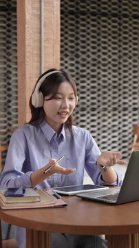Young Asian Businesswoman Working Remotely with Laptop and Smartphone in Traditional Wooden Cafe, Digital Nomad Lifestyle