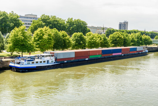 Cargo barge loaded with colourful containers tied up to a quay along the river Seine on a sunny summer day