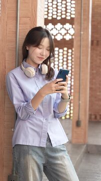 Young Asian Businesswoman Working Remotely with Laptop and Smartphone in Traditional Wooden Cafe, Digital Nomad Lifestyle