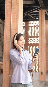 Young Asian Businesswoman Working Remotely with Laptop and Smartphone in Traditional Wooden Cafe, Digital Nomad Lifestyle